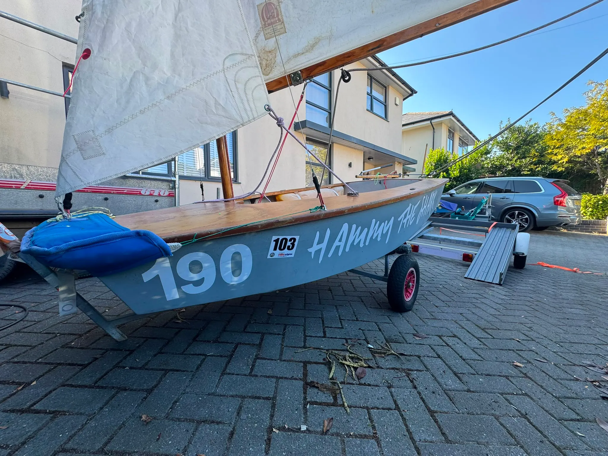 The bow, with 190 in large white figures on the grey hull, a blue foredeck cover, and a varnished side deck.